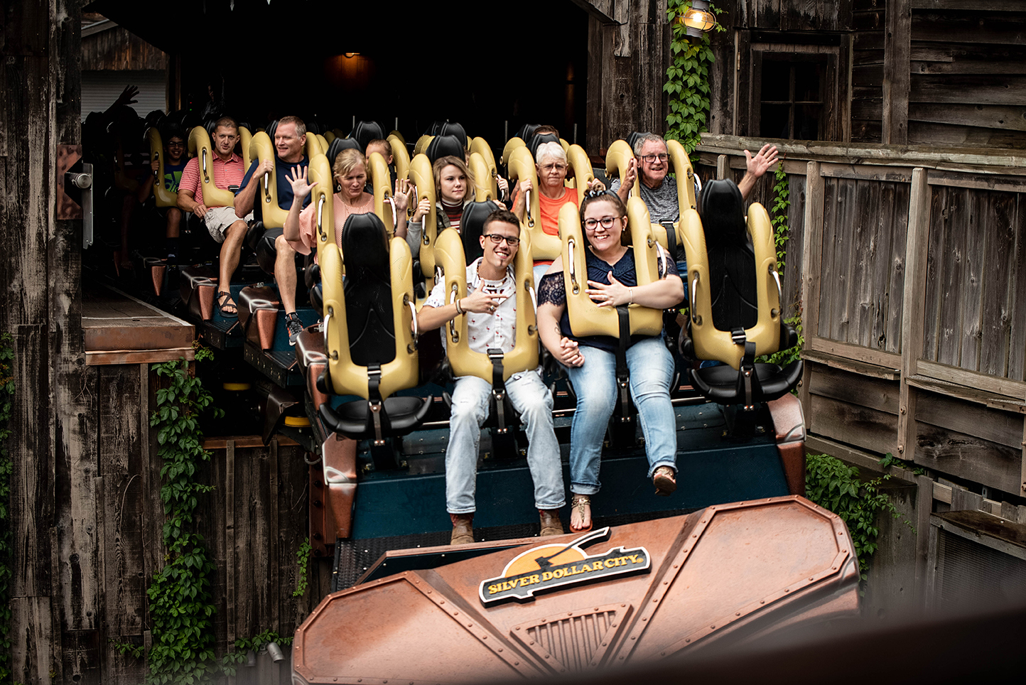 A couple points at one another riding front row at a rollercoaster at Silver Dollar City in Branson, MO