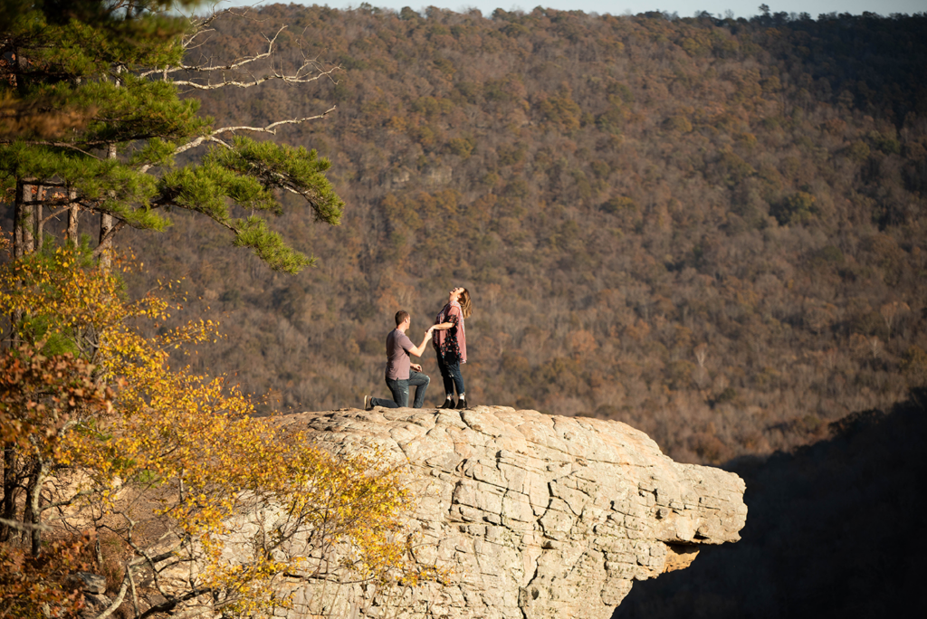 a woman throws her head back with joy being proposed to at Hawksbill Craig, Arkansas during a surprise proposal