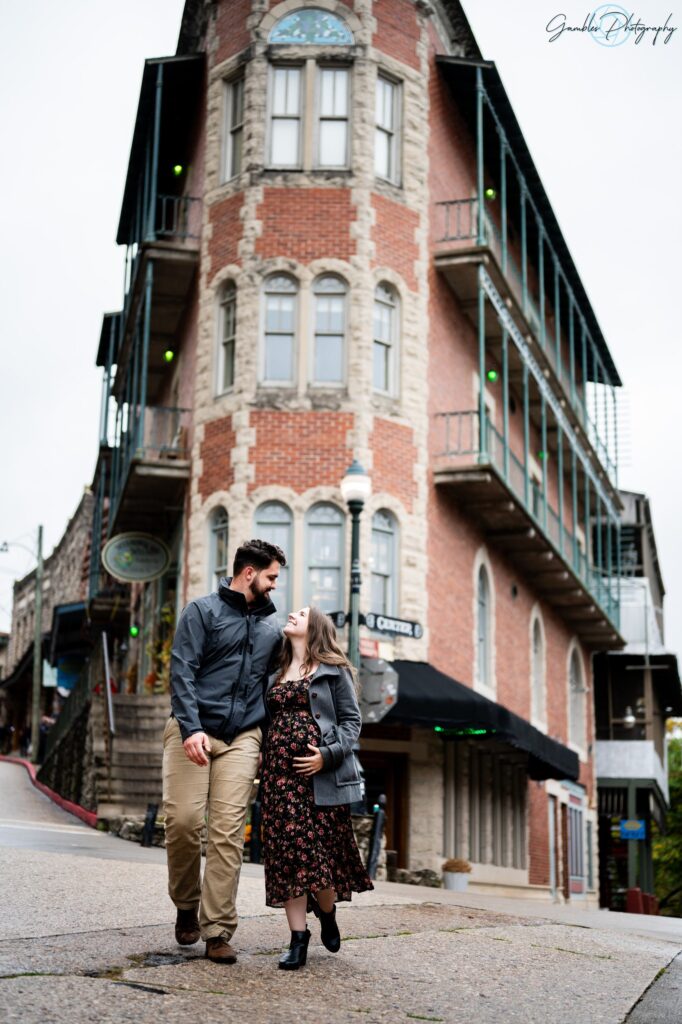 A couple loving looks at each other as they stand  in front of the Flatiron Building in Eureka Springs, AR. Photo by Gambles Photography