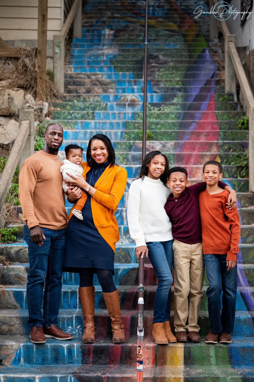 a family of 6 stands on the Rainbow Stairs in Eureka Springs, AR, during a photoshoot by Gambles Photography