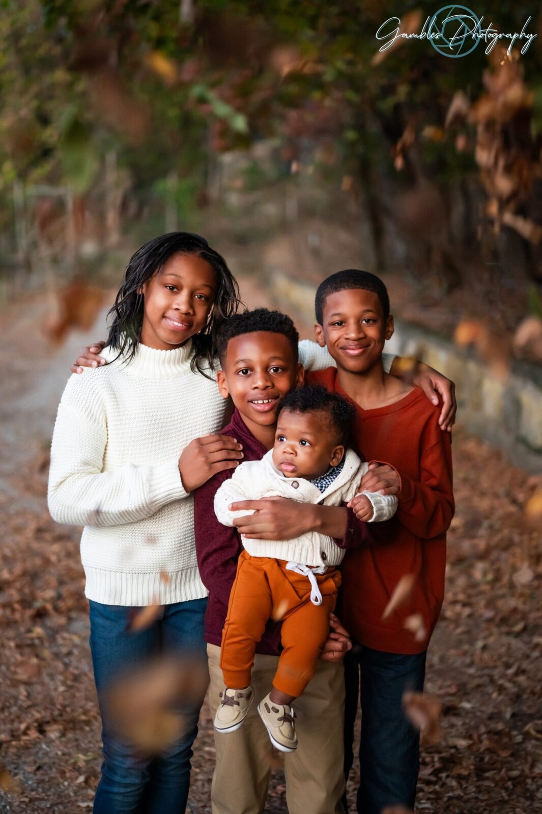 Four siblings embrace and smile at the camera during a photoshoot in Eureka Springs by Gambles Photography