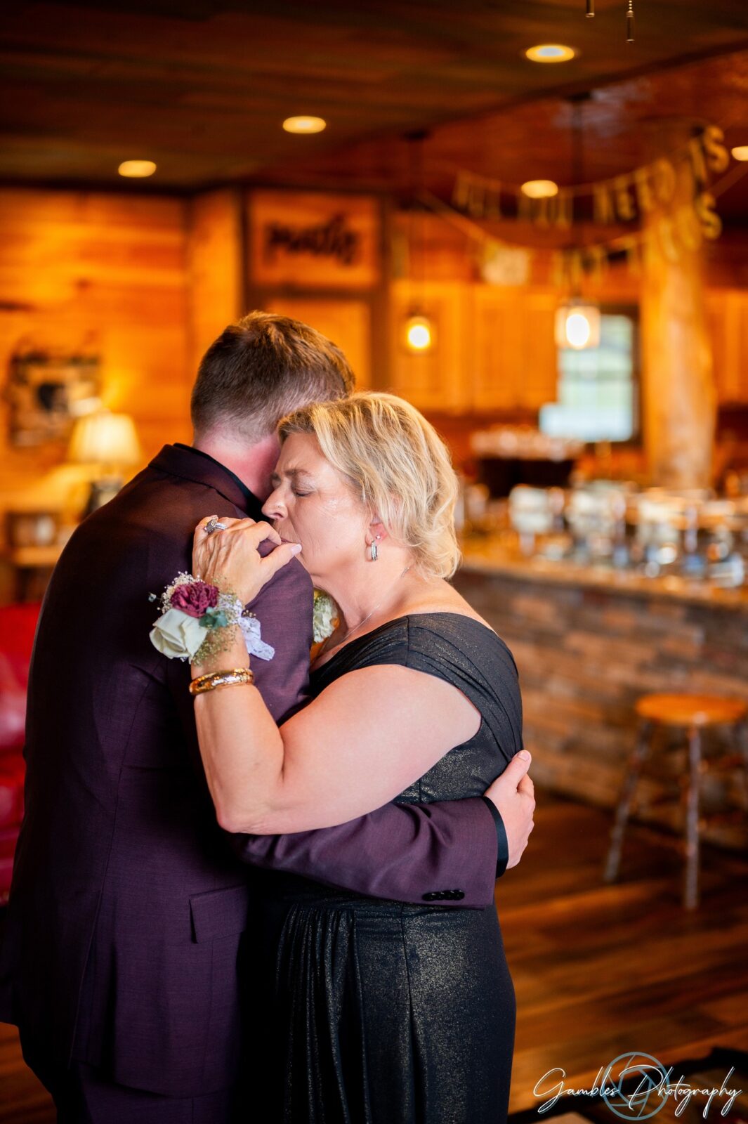 A mother and son share a first dance in a wood cabin during a wedding in the Ozarks. Photo by Gambles Photography.