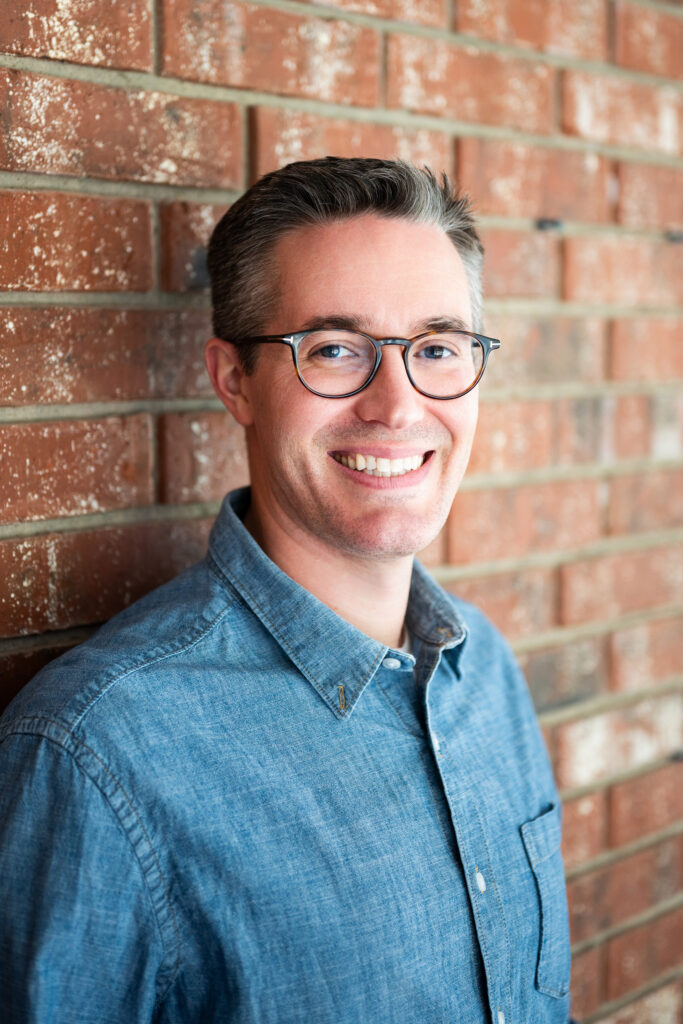 a young man poses in front of a brick wall during headshot photos near Missouri State University