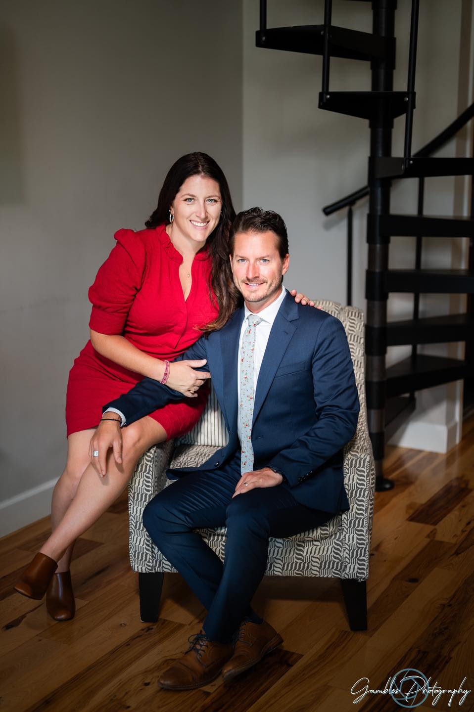 a woman in a red dress leans on her spouse during a branding photoshoot in Springfield, MO, by Gambles Photography