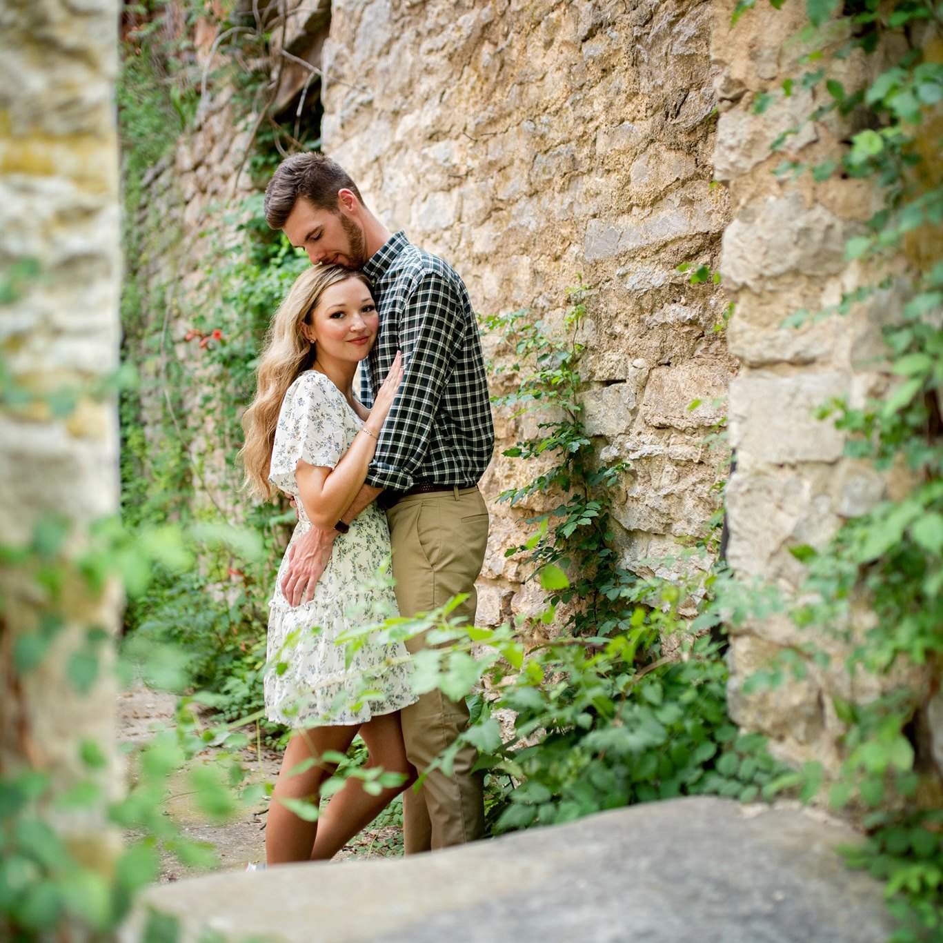 a couple huge against a tan rock wall covered in sprawling ivy during a Eureka Springs photoshoot by Gambles Photography