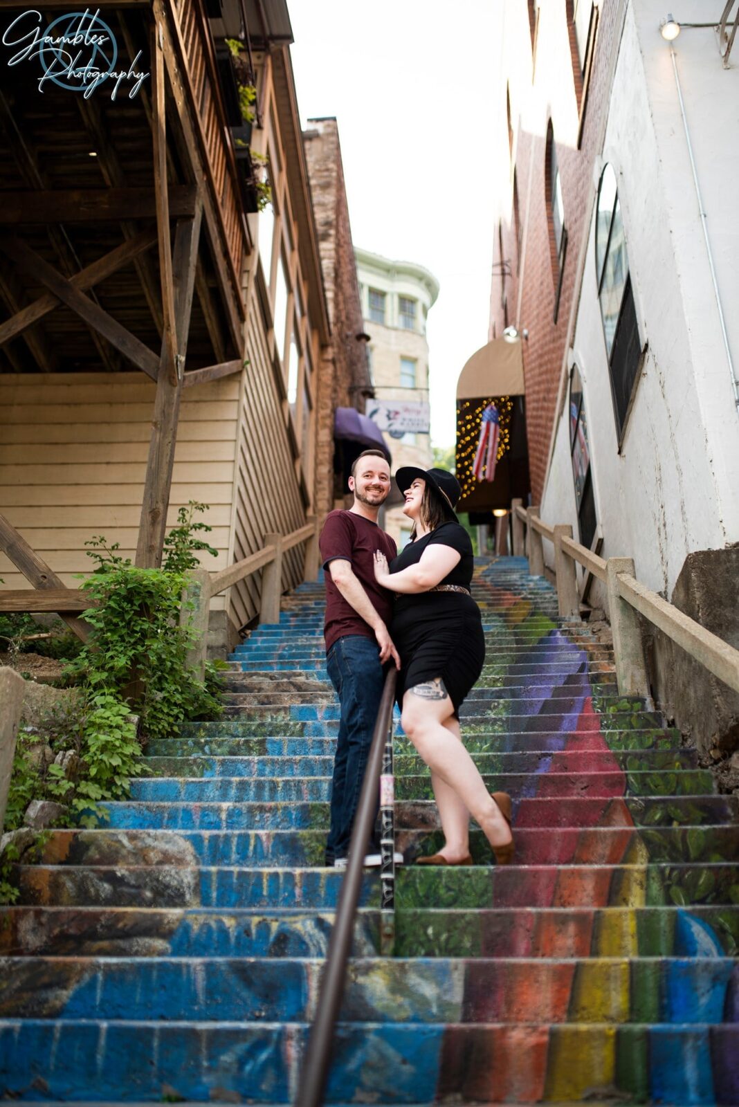 a couple poses for photos on the rainbow stairs in Eureka Springs, AR. Photo by Gambles Photography